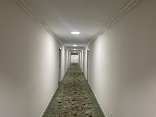 corridor with dark carpet, crown molding, and a textured ceiling