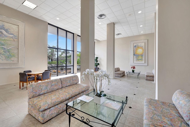 living room with floor to ceiling windows, a paneled ceiling, and light tile patterned floors