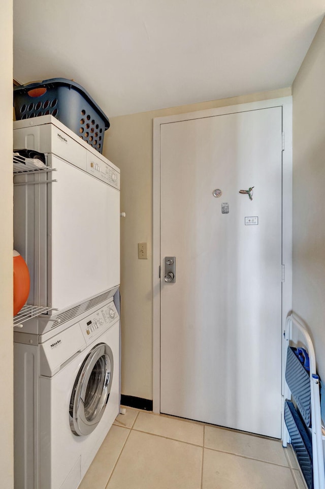 laundry room featuring stacked washer and dryer and light tile patterned floors