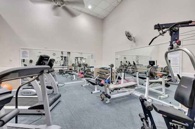 gym with a towering ceiling, a paneled ceiling, and ceiling fan