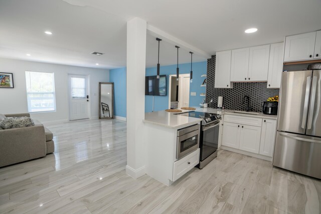 kitchen featuring white cabinetry, stainless steel appliances, sink, and hanging light fixtures