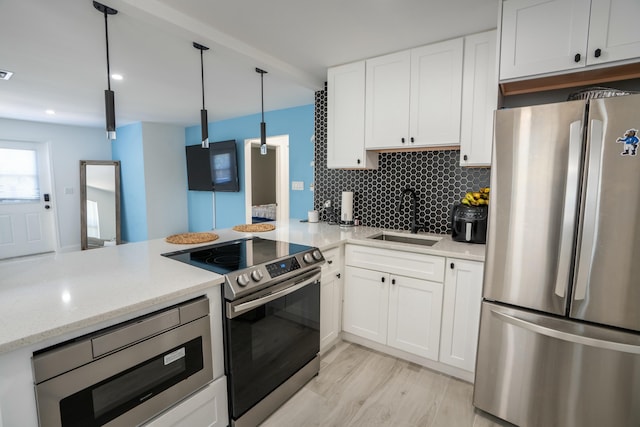 kitchen featuring sink, white cabinetry, hanging light fixtures, stainless steel appliances, and kitchen peninsula