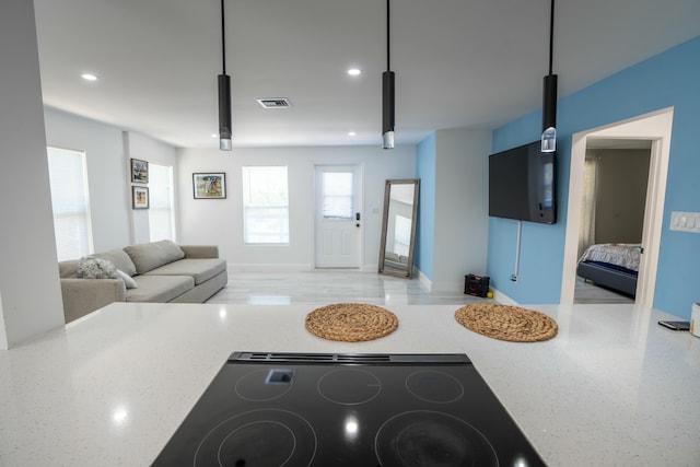 kitchen with pendant lighting, black stovetop, and light stone countertops