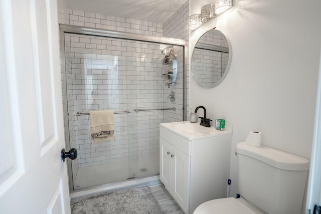 bathroom with vanity, toilet, and a shower with door