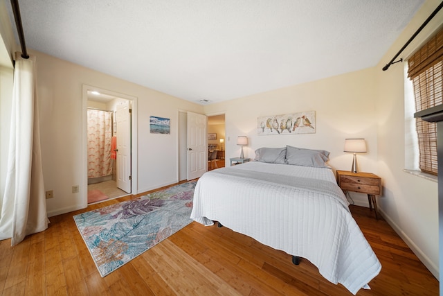 bedroom with visible vents, baseboards, light wood-style flooring, and ensuite bathroom