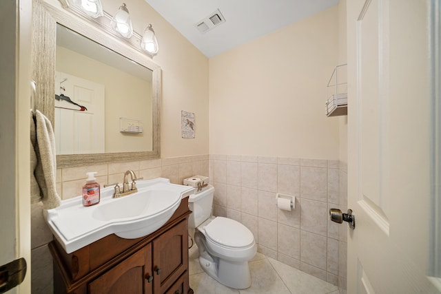 bathroom featuring vanity, visible vents, tile walls, toilet, and tile patterned floors