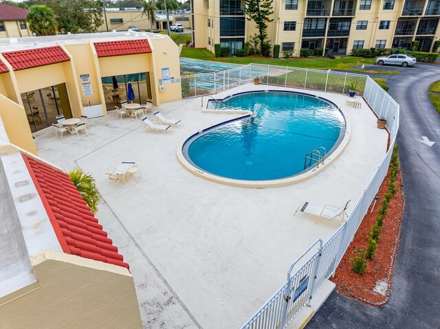 community pool with a patio area and fence