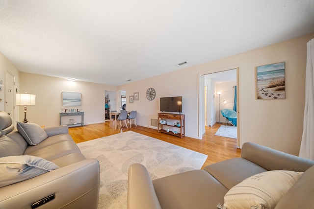 living area featuring light wood-style floors, visible vents, and baseboards