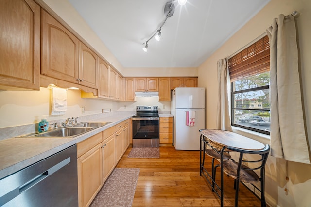 kitchen featuring light brown cabinetry, a sink, under cabinet range hood, stainless steel appliances, and light wood finished floors