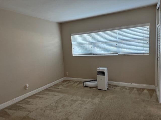 unfurnished room featuring baseboards, carpet flooring, and an AC wall unit