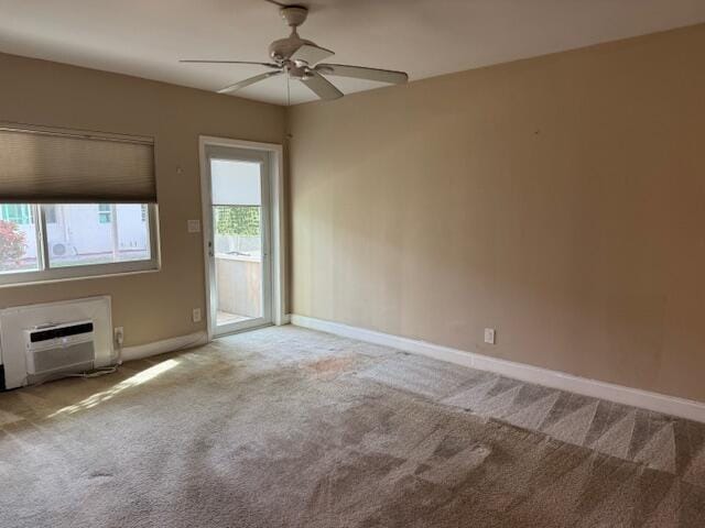 empty room featuring carpet, a wall unit AC, ceiling fan, and baseboards