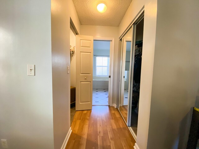 10586 Pelican Dr, Wellington, FL 33414 - hall featuring baseboards, a textured ceiling, and light wood-style floors