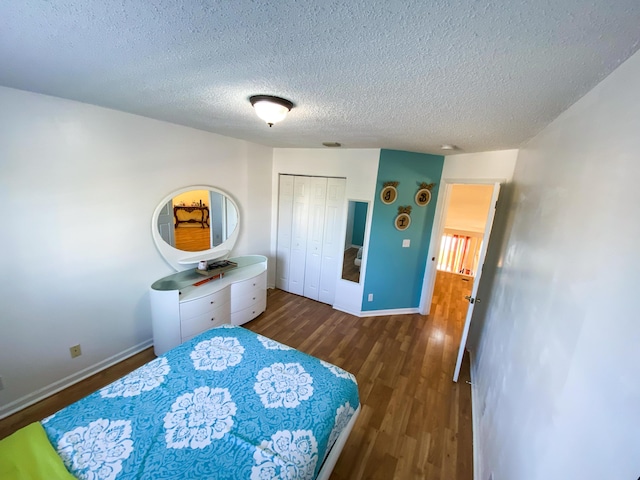 bedroom featuring visible vents, baseboards, dark wood-type flooring, a textured ceiling, and a closet