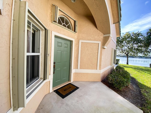 doorway to property with a water view and stucco siding