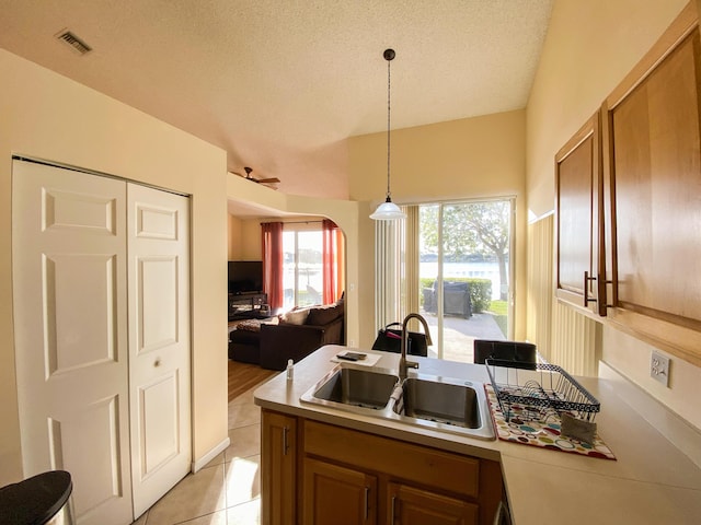 kitchen with light tile patterned floors, brown cabinetry, open floor plan, light countertops, and a sink