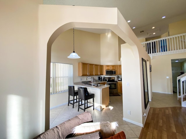 kitchen featuring brown cabinets, a kitchen breakfast bar, hanging light fixtures, stainless steel appliances, and light countertops