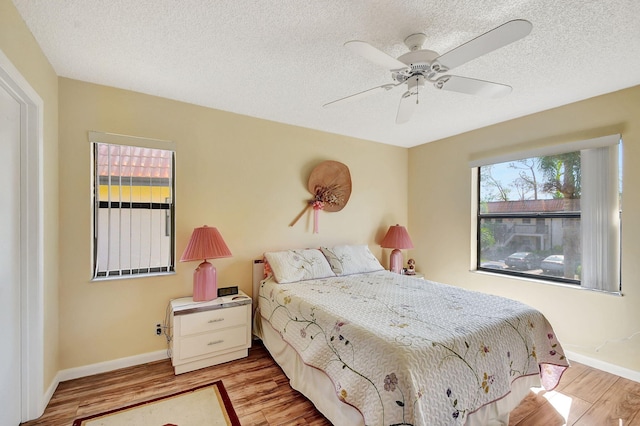 bedroom featuring ceiling fan, multiple windows, and light wood-type flooring