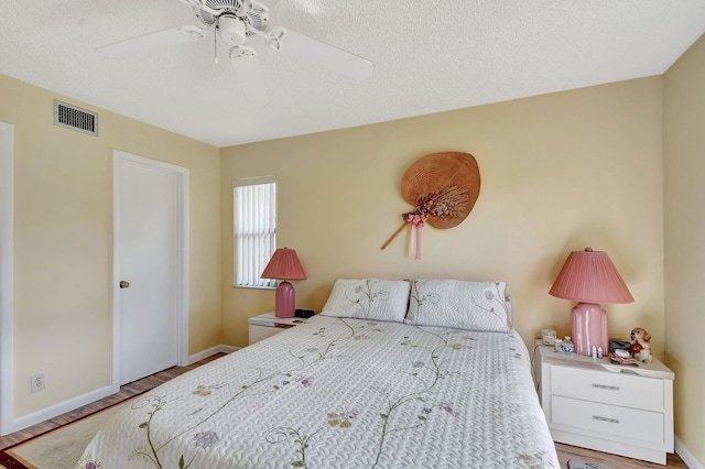 bedroom with hardwood / wood-style flooring, a textured ceiling, and ceiling fan