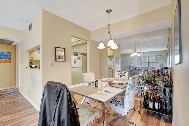 dining room with a textured ceiling and light wood-type flooring