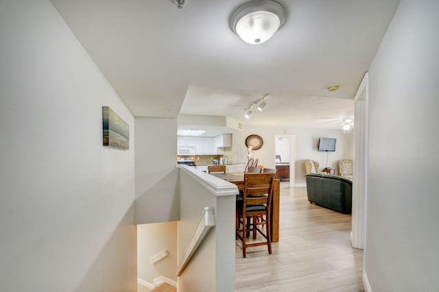 hallway featuring rail lighting and light hardwood / wood-style floors