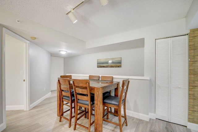 dining area with a textured ceiling and light hardwood / wood-style flooring