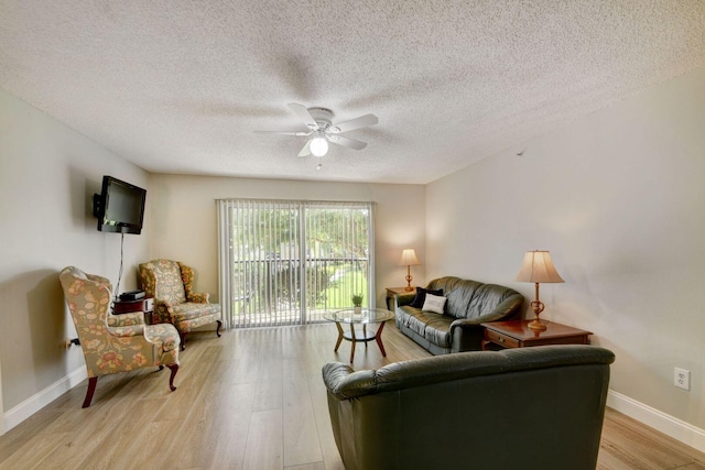 living room featuring ceiling fan, light hardwood / wood-style floors, and a textured ceiling