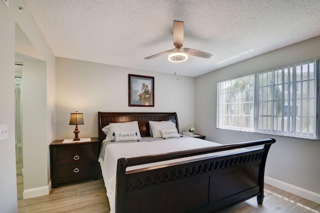 bedroom featuring a textured ceiling, ceiling fan, and light hardwood / wood-style floors