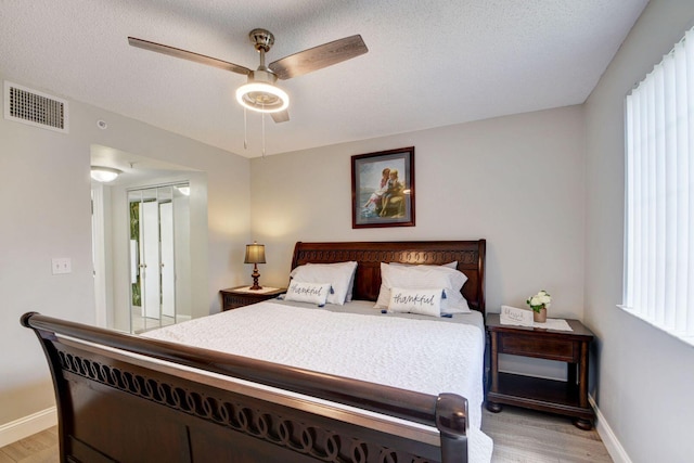 bedroom with ceiling fan, a textured ceiling, and light wood-type flooring