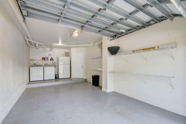 garage featuring white refrigerator and washing machine and clothes dryer