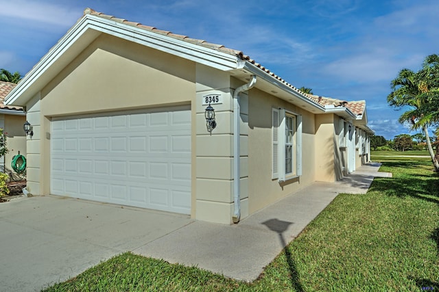 view of side of property featuring a garage and a lawn