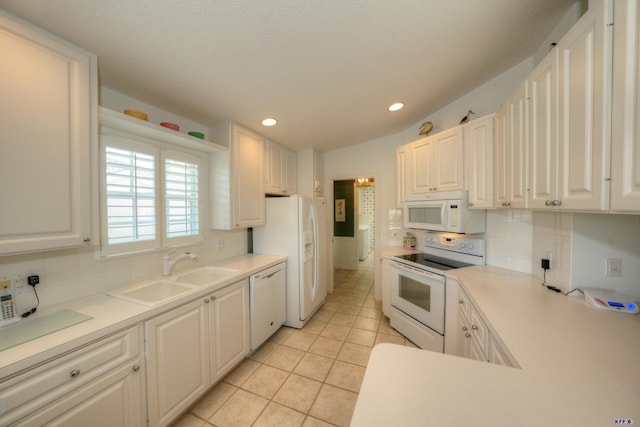 kitchen with sink, white appliances, vaulted ceiling, and white cabinets