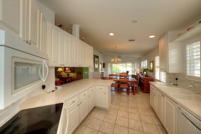 kitchen with light tile patterned floors, white appliances, white cabinetry, hanging light fixtures, and kitchen peninsula