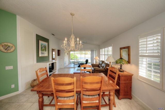 tiled dining room featuring a textured ceiling, vaulted ceiling, and a chandelier