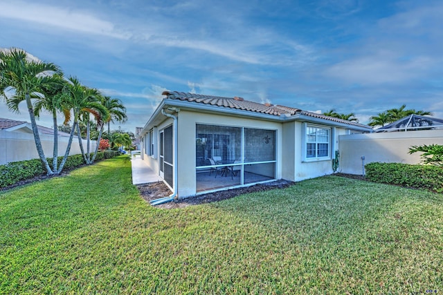 back of house with a yard and a sunroom