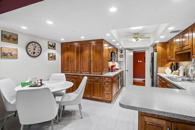 kitchen featuring a raised ceiling, sink, ceiling fan, kitchen peninsula, and stainless steel appliances