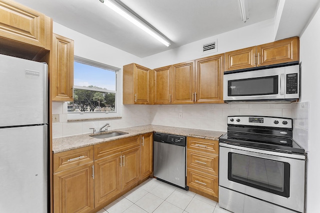 kitchen featuring light stone counters, sink, decorative backsplash, and stainless steel appliances