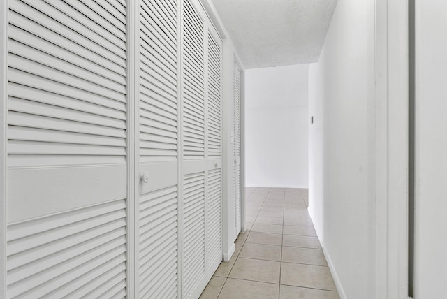 hall with light tile patterned flooring and a textured ceiling