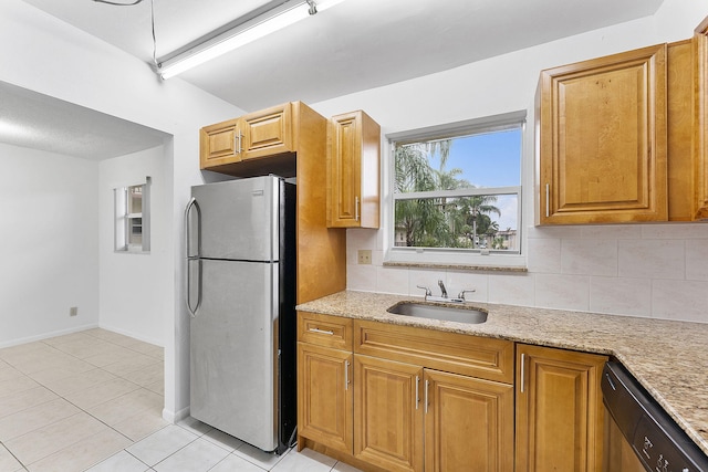 kitchen with tasteful backsplash, stainless steel appliances, light stone countertops, and sink