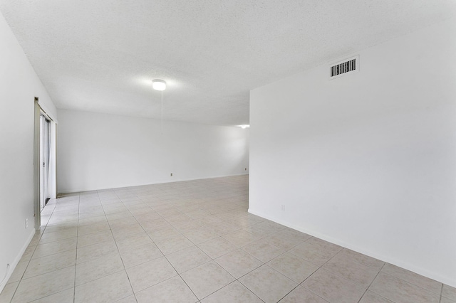 empty room with a textured ceiling and light tile patterned floors