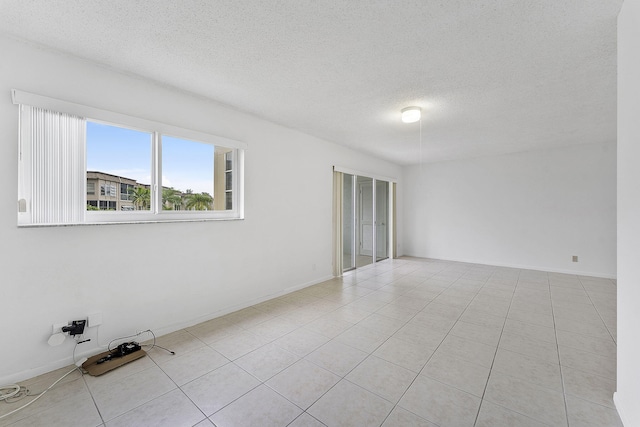 spare room featuring a textured ceiling and light tile patterned floors