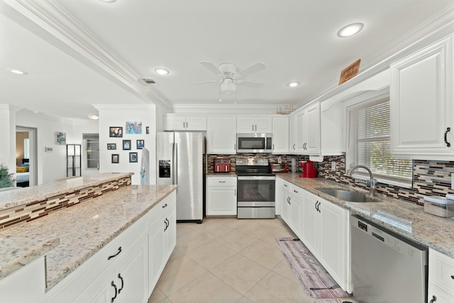 kitchen featuring sink, ornamental molding, stainless steel appliances, light stone countertops, and white cabinets