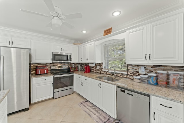 kitchen featuring appliances with stainless steel finishes, white cabinetry, sink, light tile patterned floors, and light stone counters