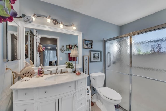 bathroom with vanity, a shower with door, and toilet