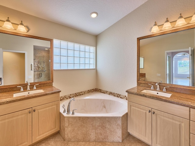 bathroom with tile patterned flooring, plus walk in shower, vanity, and a textured ceiling