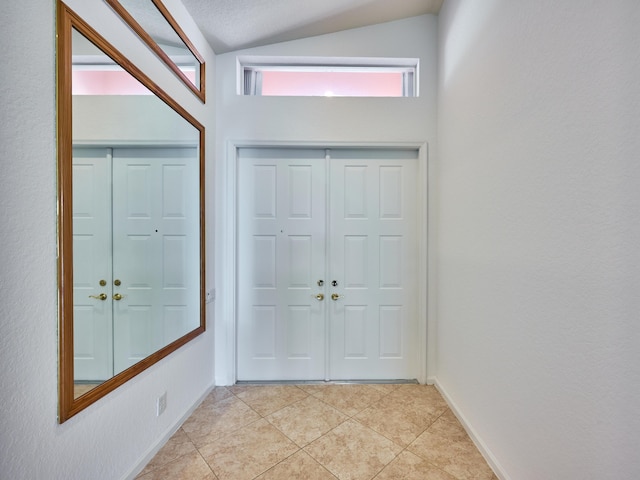 entrance foyer with light tile patterned flooring and lofted ceiling