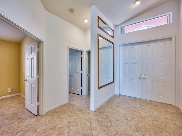 foyer featuring light tile patterned flooring, vaulted ceiling, and a textured ceiling