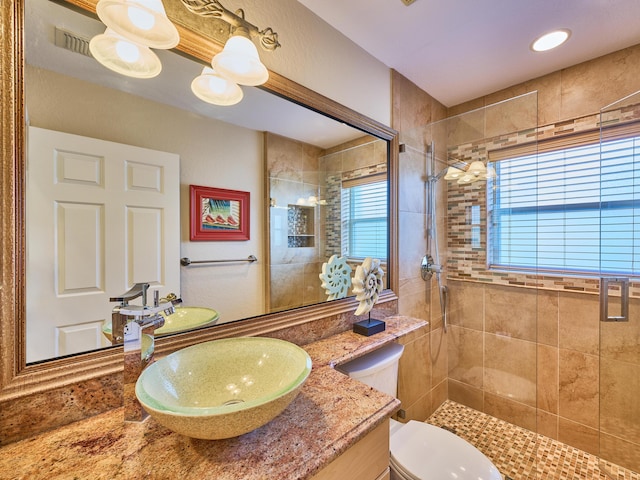 bathroom with vanity, tiled shower, and toilet