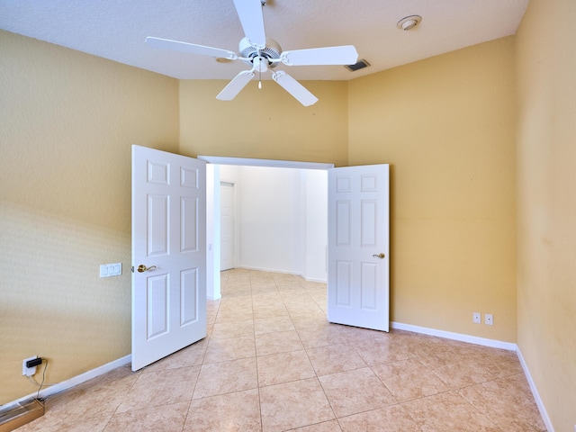 tiled spare room with ceiling fan