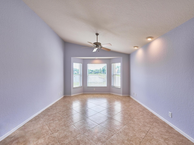 empty room with lofted ceiling, light tile patterned floors, a textured ceiling, and ceiling fan