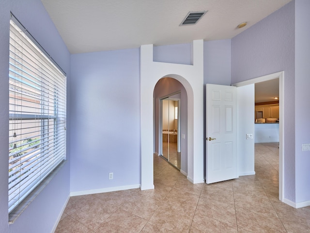 unfurnished room featuring light tile patterned flooring and a towering ceiling